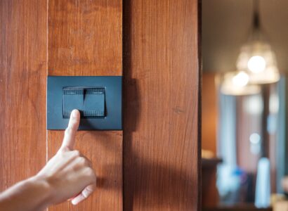 finger turns on light switch on wall at home