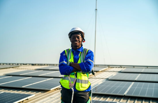 smiling man standing among rooftop solar panels