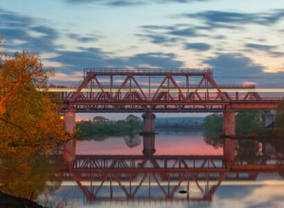 Railway bridge over the river at sunset with blurred light on a passing train - Texas