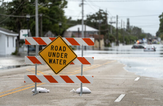 Flooded street with road closed sign blocking driving of cars in Sarasota, Florida. Safety of transportation during natural disaster concept.